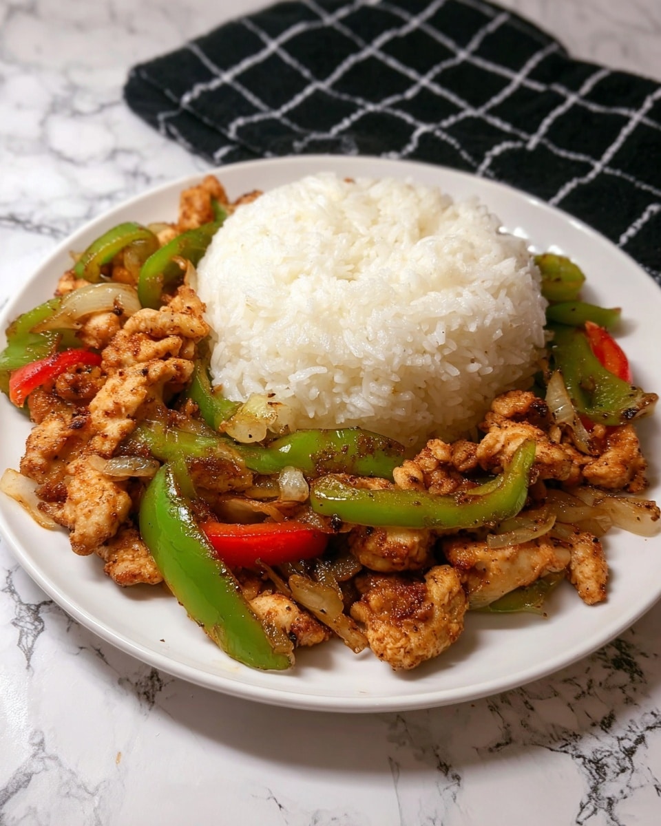 A white plate with a mound of white rice at the top center, soft and fluffy in texture. Below the rice, there is a mix of golden-brown cooked chicken pieces with crispy edges, mixed with bright green sliced bell peppers and small bits of cooked onions, giving a colorful and textured look. The food is placed on a surface with a white marbled texture, and behind the plate is a black cloth with a white grid pattern. Photo taken with an iphone --ar 4:5 --v 7