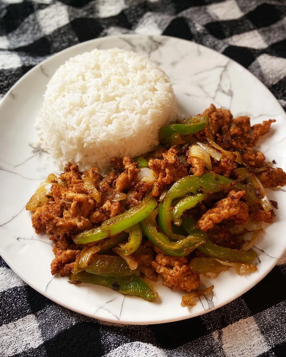 A white marbled plate holds two main layers: at the back, a mound of plain white rice with a soft, fluffy texture and slightly rounded top, and in front, a generous serving of cooked chicken pieces mixed with sliced green bell peppers and small bits of cooked onions. The chicken pieces have a crispy, browned look with a rough texture, while the green peppers are tender and glistening, adding a fresh contrast. The white marbled plate sits against a black and white checkered fabric background. photo taken with an iphone --ar 4:5 --v 7