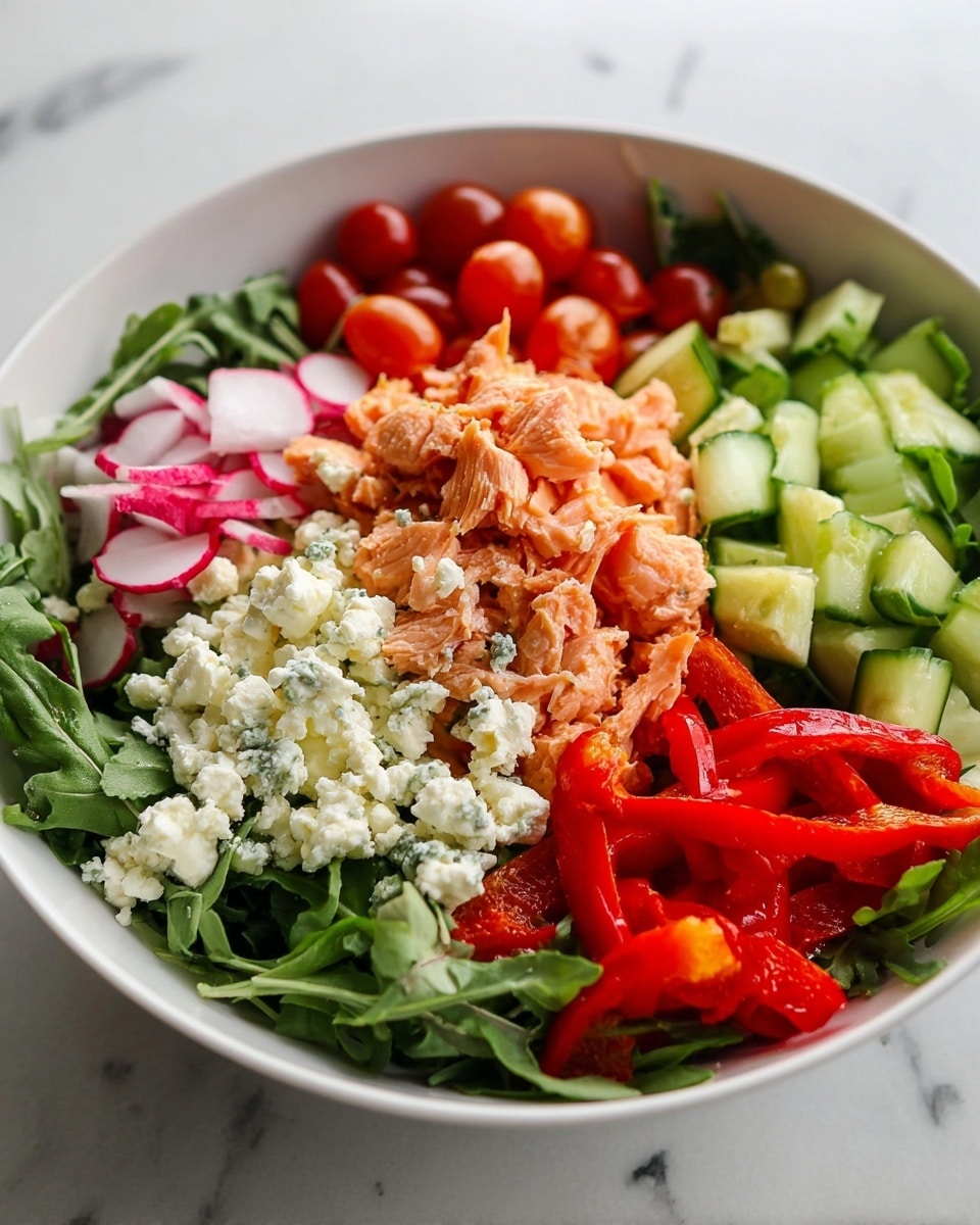 The image shows a white bowl filled with a fresh salad on a white marbled surface. The bottom layer is dark green arugula leaves spread evenly. On top of that, there are soft orange pieces of cooked salmon scattered in the center. To one side of the salmon, there are bright red roasted bell pepper pieces with a slight charred texture. Around the salmon, thinly sliced radishes with white and red edges are placed, along with round, pale green cucumber slices. Small crumbled white cheese pieces are sprinkled over the salmon, adding softness and contrast. The overall look is colorful, fresh, and vibrant. photo taken with an iphone --ar 4:5 --v 7