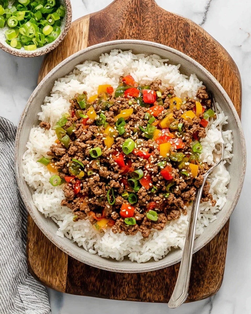 The image shows a bowl with two layers: a bottom layer of white rice and a top layer of cooked ground beef mixed with diced red, green, and yellow bell peppers, sprinkled with sesame seeds and chopped green onions. A silver fork is resting inside the bowl, slightly lifting some beef and peppers. The bowl is white and placed on a wooden board, with a small bowl of sliced green chili peppers nearby on a white marbled surface. Photo taken with an iphone --ar 4:5 --v 7