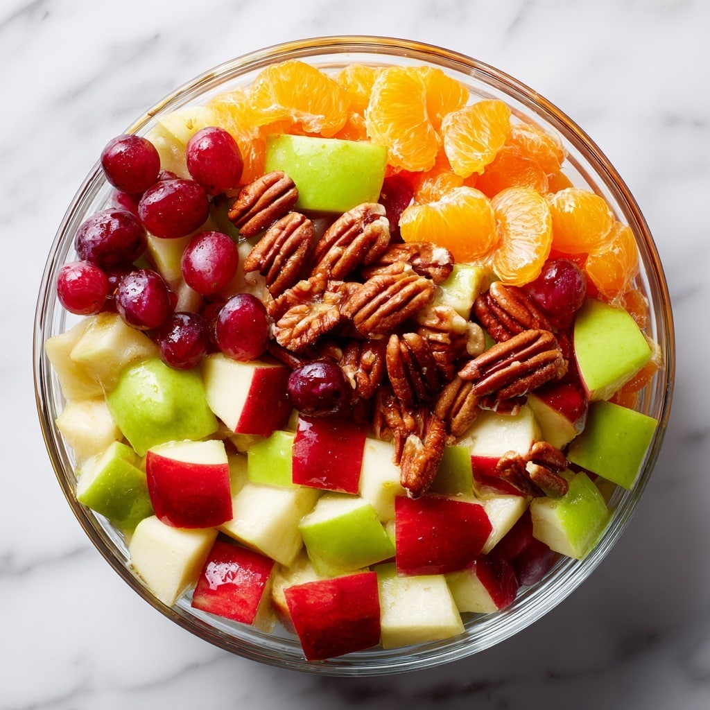 A clear glass bowl filled with a colorful fruit salad sits on a white marbled surface. The salad has roughly three layers: the bottom layer is made up of chopped red and green apples with smooth, shiny skins in red, green, and white tones; the middle layer is scattered with bright orange chunks of peeled oranges with a juicy texture; the top layer is sprinkled with whole red grapes, dried cranberries that are dark red and wrinkled, and pecan halves that have a brown, natural wood-like texture. Photo taken with an iphone --ar 4:5 --v 7
