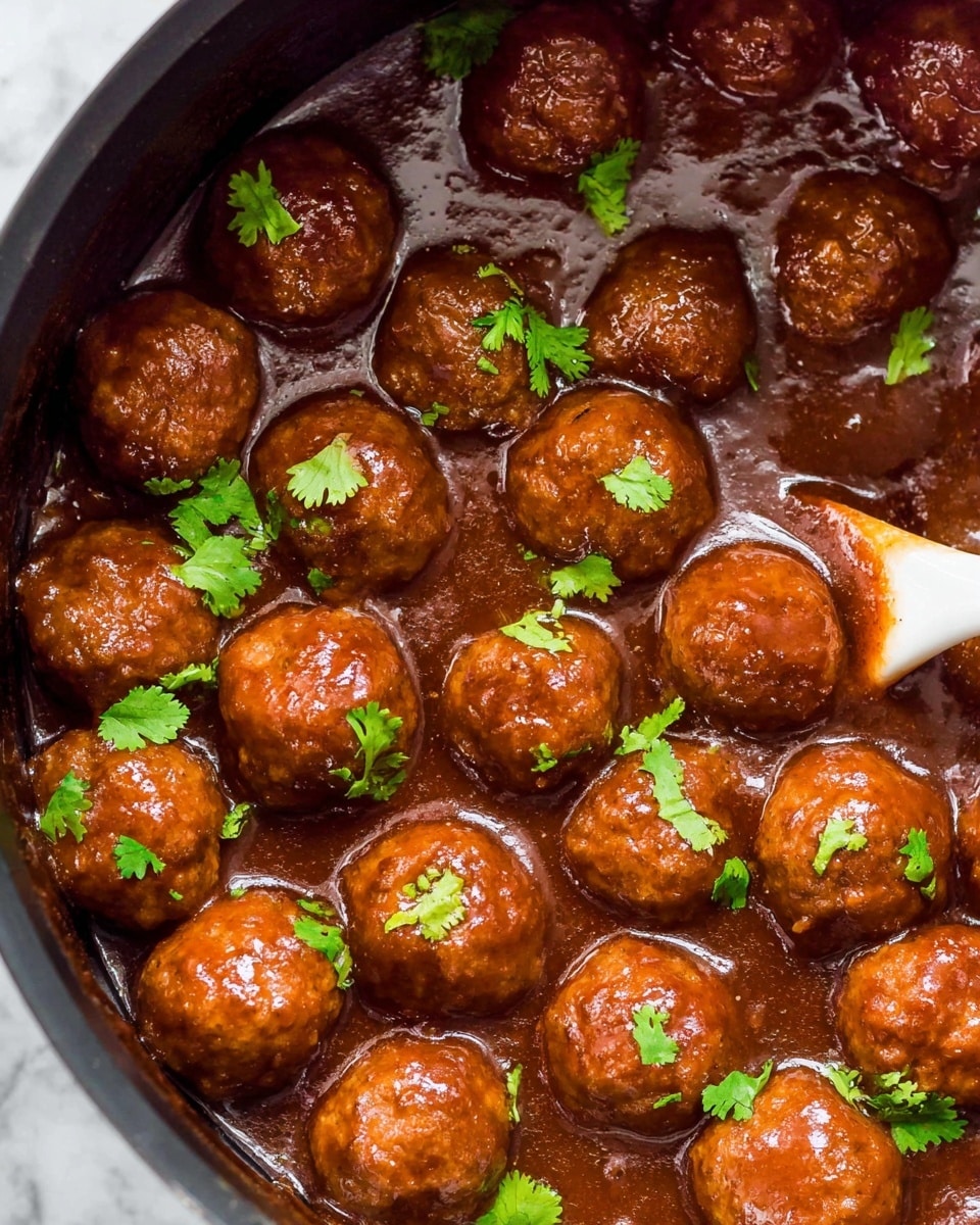 The image shows many shiny, brown meatballs covered in a thick dark sauce inside a black slow cooker. The meatballs are topped with scattered small bright green cilantro leaves. A light wooden spoon with a white scoop is partially submerged in the sauce, lifting a few meatballs. The overall look is glossy and fresh with the contrast of dark sauce and green herbs. Photo taken with an iphone --ar 4:5 --v 7