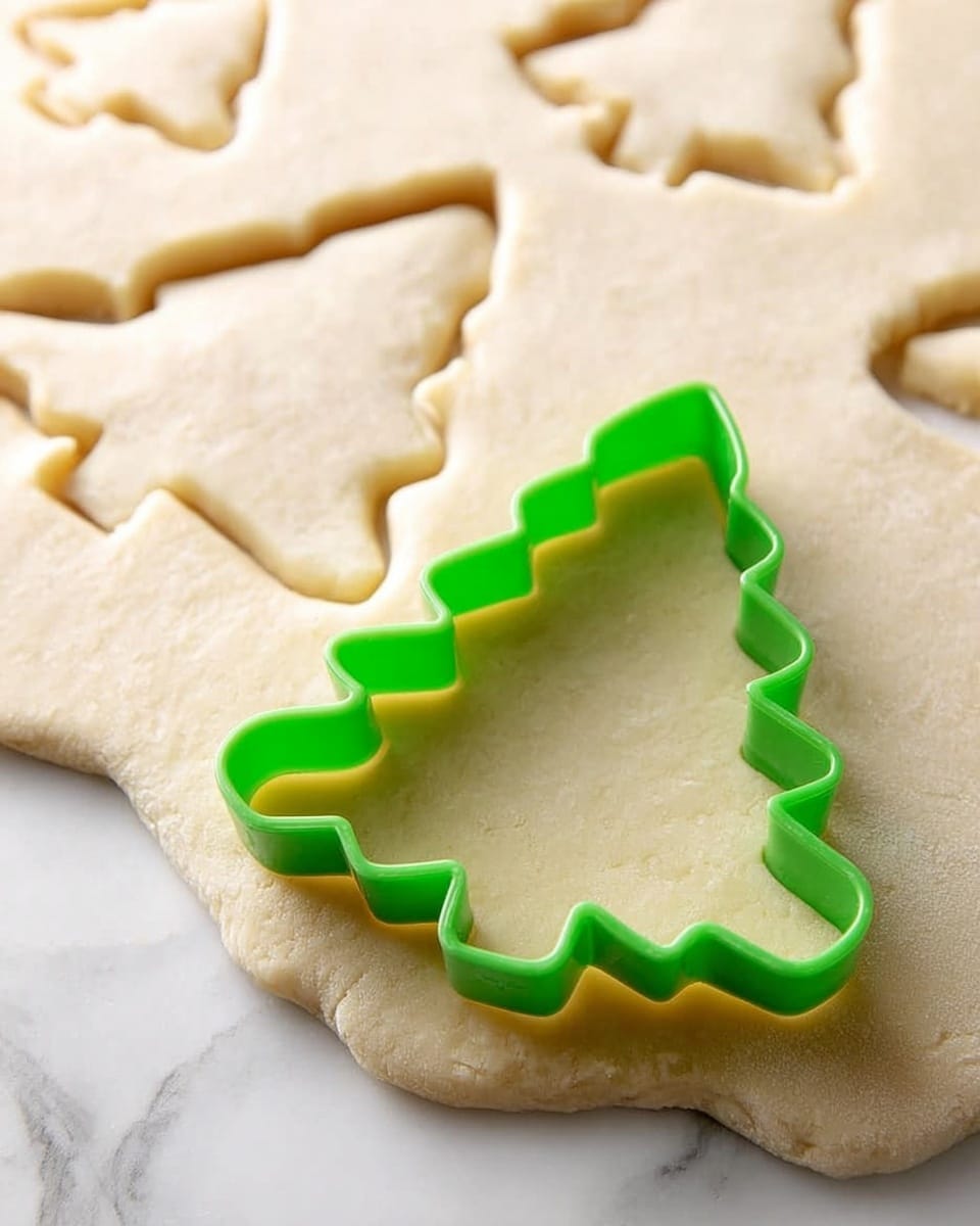 The image shows several pale beige sugar cookies shaped like a snowflake, mitten, Christmas tree, and other holiday shapes cooling on a metal rack. All the cookies have a smooth surface with no icing or decoration and a soft texture. The close-up view focuses on one large snowflake-shaped cookie in the center with sharp, defined edges. The metal rack is placed on a white marbled surface that adds subtle contrast without drawing attention. photo taken with an iphone --ar 4:5 --v 7