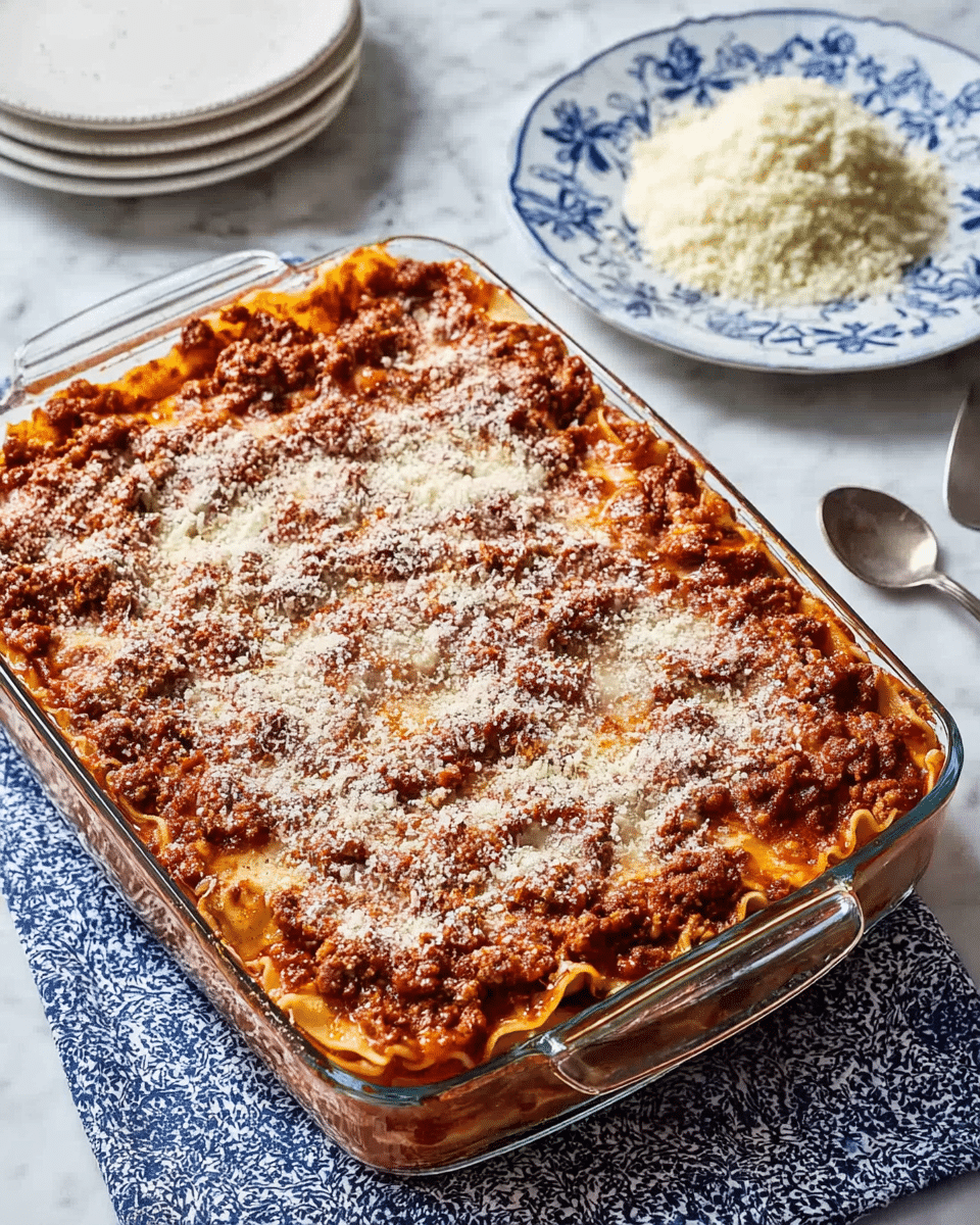 A piece of lasagna sits on a white plate, showing four visible layers of pasta sheets that are light yellow with slightly browned edges. The top layer is melted cheese with a golden-brown crust and scattered slices of cooked mushrooms that are dark brown. Below that, creamy white sauce mixed with bits of cooked spinach and shredded chicken fills the middle layers. Some finely chopped green herbs are sprinkled on top, with a single fresh green leaf as garnish. The plate is set on a white marbled surface. photo taken with an iphone --ar 4:5 --v 7