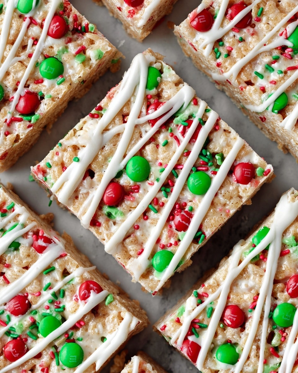 The image shows a close-up of a square treat with two visible layers. The bottom layer is a light golden, crispy puffed rice base mixed with colorful red and green sprinkles. The top layer is decorated with shiny red and green candies embedded evenly, and white icing is drizzled across the entire surface in thin lines. Some candies and sprinkles are scattered around on the white marbled surface beneath the treat, which rests on a piece of light brown parchment paper. A white dish filled with red and green candies is partially visible at the bottom of the image. Photo taken with an iphone --ar 4:5 --v 7