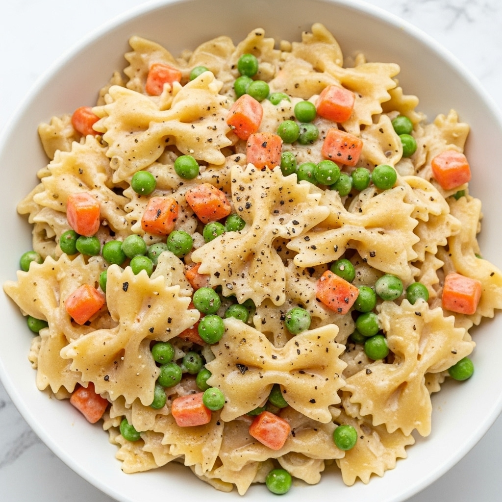 The image shows three white bowls filled with a creamy pasta dish featuring farfalle pasta mixed with pieces of chicken, green peas, and small carrot chunks. Each layer has the light yellow pasta with a smooth, creamy texture, scattered with soft white chicken pieces, bright orange carrot bits, and vibrant green peas evenly distributed. One of the bowls has a white spoon placed on its side. In the background, there is a glass of water with a slice of lemon inside. All are set on a white marbled surface, creating a clean and fresh look. photo taken with an iphone --ar 4:5 --v 7