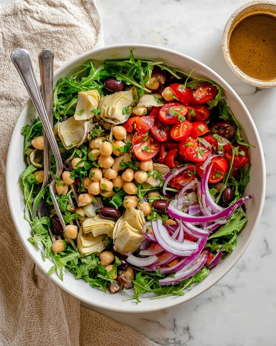 A large white bowl filled with a fresh salad that has several layers: the bottom layer is bright green arugula leaves, followed by scattered light beige artichoke hearts. On top, there are halved red cherry tomatoes, beige chickpeas, thin slices of purple-red onion, black olives, and some flat parsley leaves. Two silver forks rest inside the bowl, one on the left and one on the right. The bowl sits on a white marbled surface next to a light beige cloth and a small round container with brown dressing. photo taken with an iphone --ar 4:5 --v 7