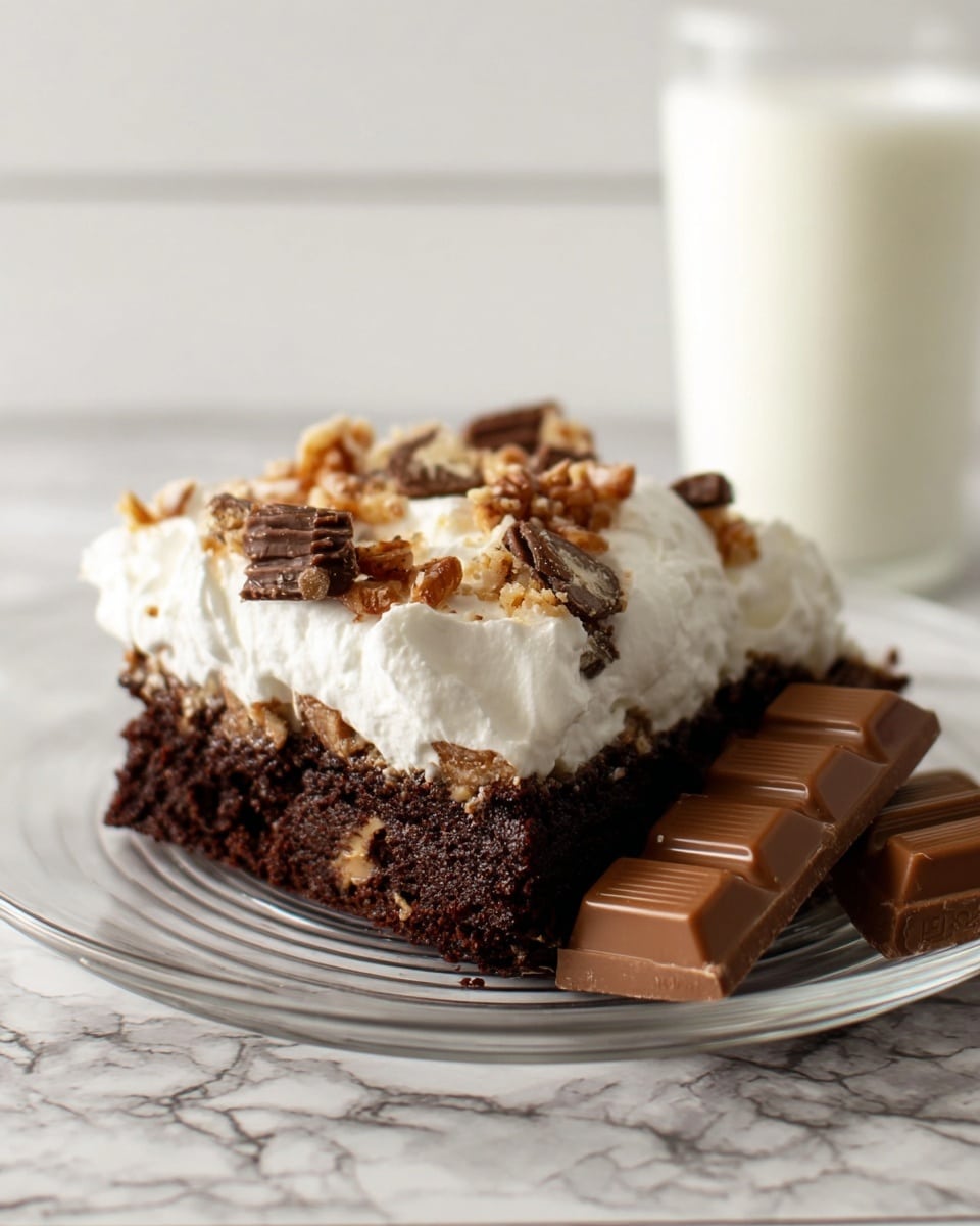 A square piece of chocolate cake sits on a clear glass plate placed on a white marbled surface. The cake has two visible layers: the bottom layer is a moist, dark brown chocolate base with a rich texture, while the top layer is thick white whipped cream, soft and fluffy, spread unevenly with some peaks. Small pieces of crushed chocolate and nuts are scattered on the whipped cream, adding a rough texture and some light brown and beige colors. Next to the cake on the right side of the plate, there are two smooth, rectangular milk chocolate bars leaning slightly against the cake. In the background, a blurred white glass of milk is visible, complementing the scene. Photo taken with an iphone --ar 4:5 --v 7