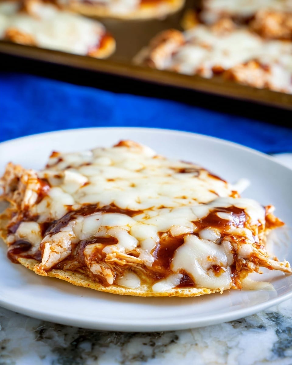 Two small round flat tortillas lie on a black baking tray with melted white cheese covering most of their surface. Under the cheese, shredded light brown chicken pieces are visible, and dark brown sauce is drizzled unevenly over the cheese in thick streaks. The tortillas' edges show slight browning and crispness, and some melted cheese has spread onto the tray around the tortillas. The tray rests on a white marbled texture surface. photo taken with an iphone --ar 4:5 --v 7