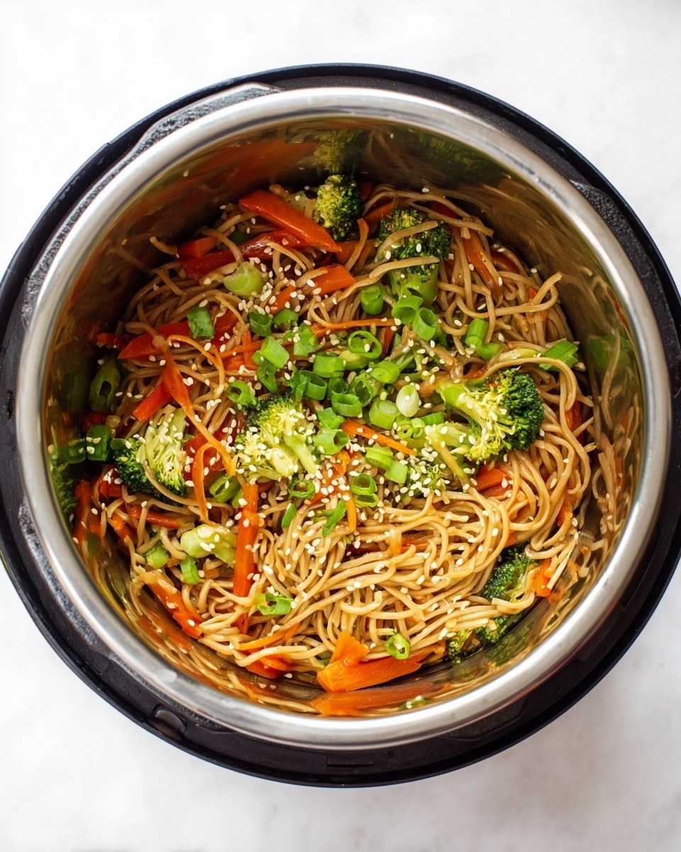 Inside a stainless steel pot, there is a colorful noodle dish with three main layers visible. The base layer is made of light brown noodles, soft and tangled, filling the pot. Mixed throughout the noodles, the second layer consists of bright orange carrot sticks and green broccoli florets, adding a fresh, crunchy texture. The top layer is sprinkled with chopped green onions and white sesame seeds, giving a fresh and slightly textured finish. The photo is taken from above, showing all the food inside the pot clearly, with a white marbled background. photo taken with an iphone --ar 4:5 --v 7