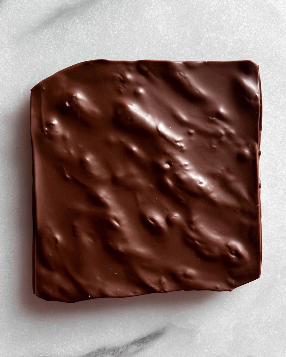 A smooth, thick square layer of dark chocolate covers the entire surface, showing slight dimples and a glossy texture with a few irregular bumps. The chocolate layer is uniform and shiny, set on a white marbled textured background, emphasizing the rich, dark brown color. Photo taken with an iphone --ar 4:5 --v 7