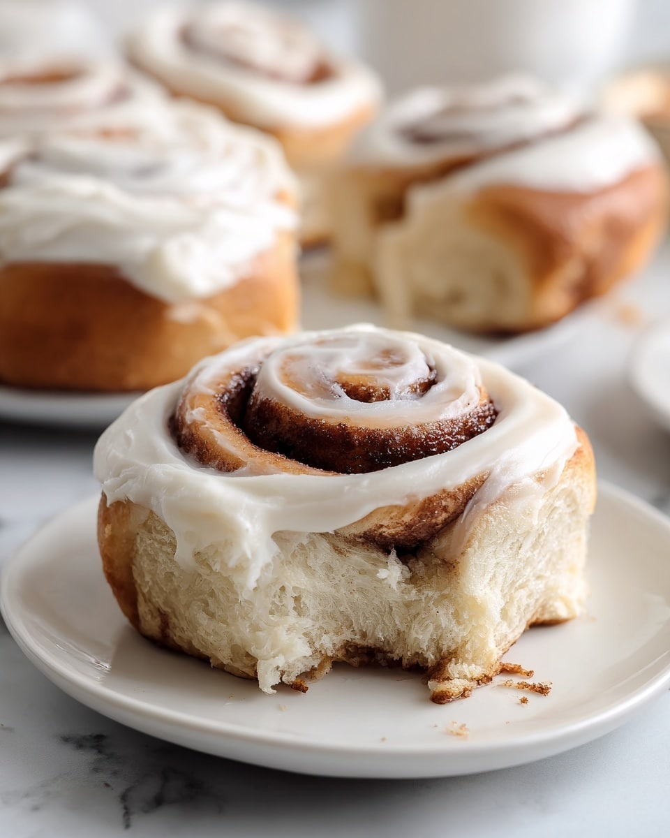 A close-up view of nine cinnamon rolls arranged in a 3x3 grid inside a baking pan lined with brown parchment paper. Each roll shows a tight spiral pattern with light beige dough layers wrapped around a darker brown cinnamon filling. The dough looks soft and smooth with a slightly glossy texture, while the cinnamon filling has a grainy texture. The pan sits on a white marbled surface, and natural lighting highlights the contrast between the creamy dough and the cinnamon swirls. photo taken with an iphone --ar 4:5 --v 7
