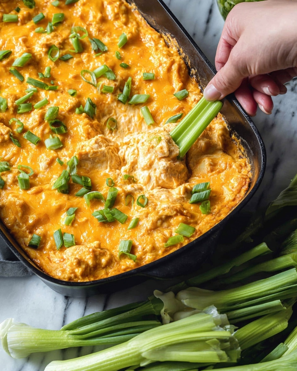 A black baking dish filled with a creamy, orange cheddar cheese dip with a thick, slightly uneven texture, sprinkled with chopped green scallions on top for contrast. A woman's hand holds a bright green celery stick dipped into the cheesy mixture, showing the dip clinging to the celery with a rich, gooey look. To the side, fresh green scallions lay on a white marbled surface, complementing the colors in the dish. The scene is bright and inviting with a close-up view highlighting the texture and colors. photo taken with an iphone --ar 4:5 --v 7